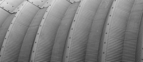 Rows of curved corrugated metal roof panels fixed on exposed seams