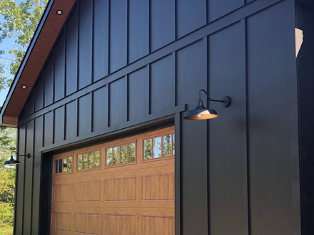 Dark board-and-batten fiber cement siding on a gabled elevation above a timber garage door