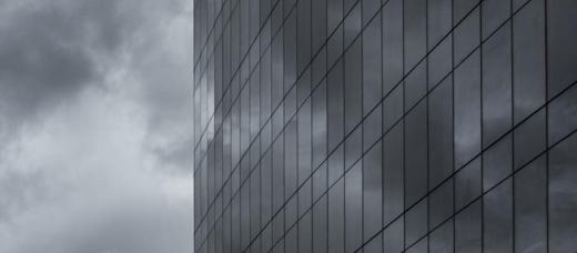 Panelised curtain wall rising into a heavy overcast sky
