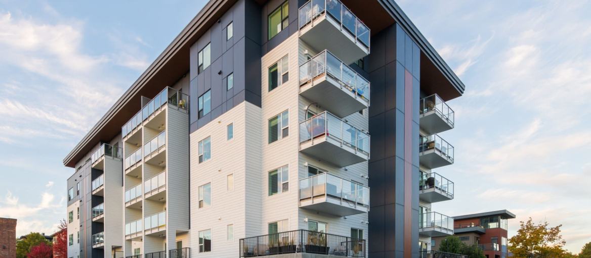 Five-storey mixed-use building at 468 West Ave, Vancouver, clad in white and charcoal plank siding with aluminium reveals between the fields
