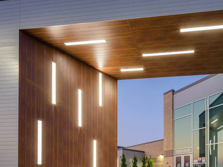 Wood-look soffit and column cladding under a lit entry canopy